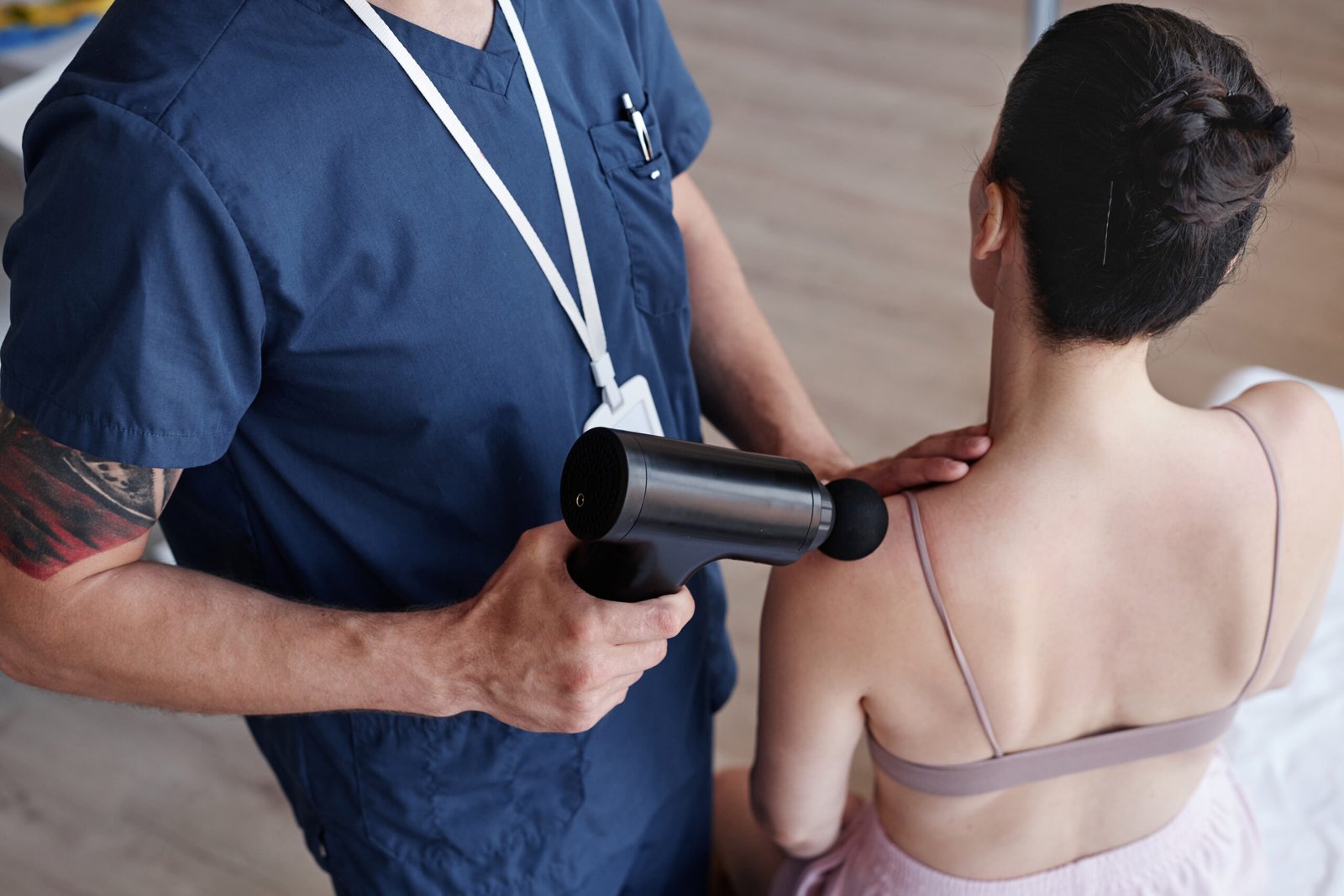 Vista desde arriba de terapeuta usando masajeador en paciente durante procedimiento médico